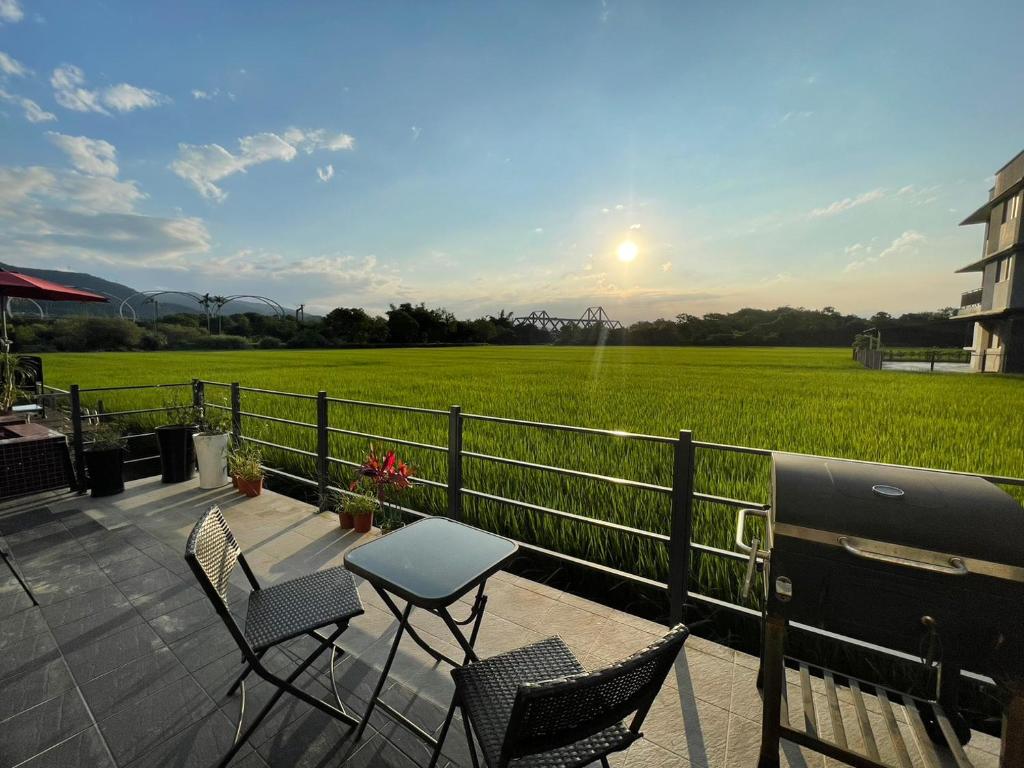 eine Terrasse mit einem Tisch, Stühlen und einem Feld in der Unterkunft Sunrise Inari B&B in Dongshan