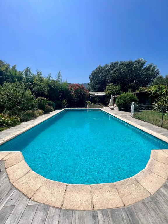 une grande piscine bleue avec une terrasse en bois dans l'établissement Domaine du Lac de la vallée, à La Roquette-sur-Siagne