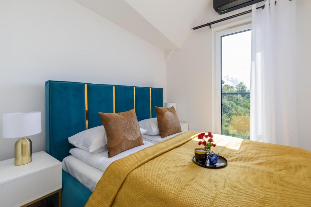 a bedroom with a bed with a blue headboard and a window at Exclusive Apartment Różana with AC & Balcony View 1 km to the Beach by Renters in Sianozety