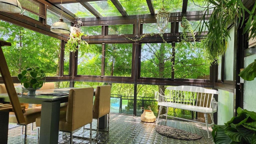 a conservatory with a table and chairs and windows at Najima B&B in Jian