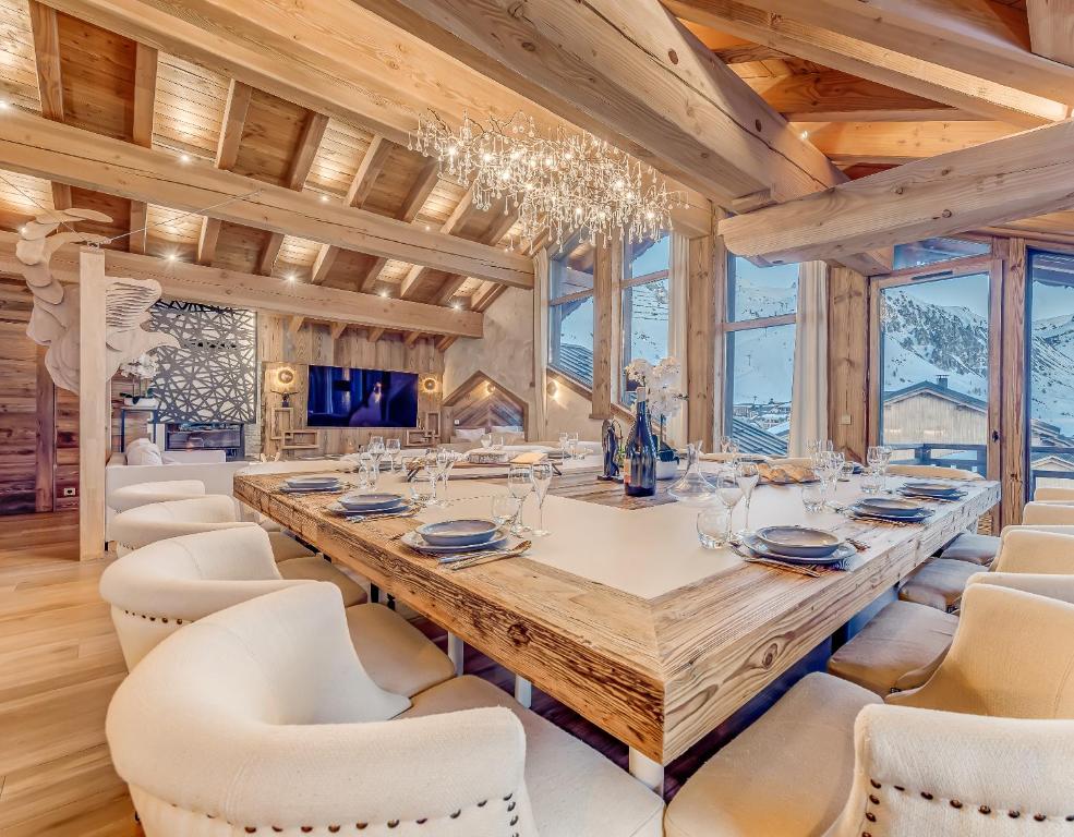 a dining room with a large wooden table and white chairs at Chalet ANNAPURNA Lodge GANGA 5 étoiles in Tignes