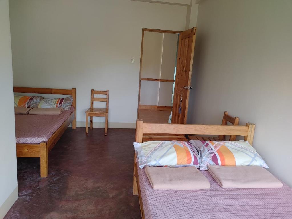 a room with two beds and a chair at Cam-Jhao's Homestay in Sagada