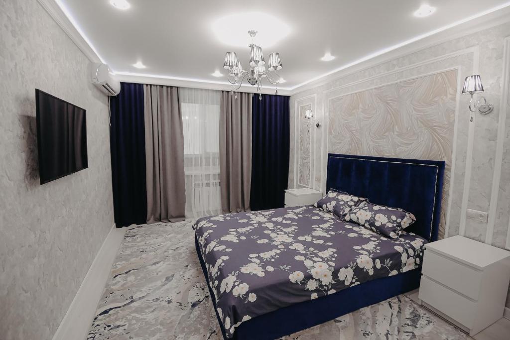 a bedroom with a blue bed and a chandelier at VIP апартаменты однокомнатная квартира in Uralsk