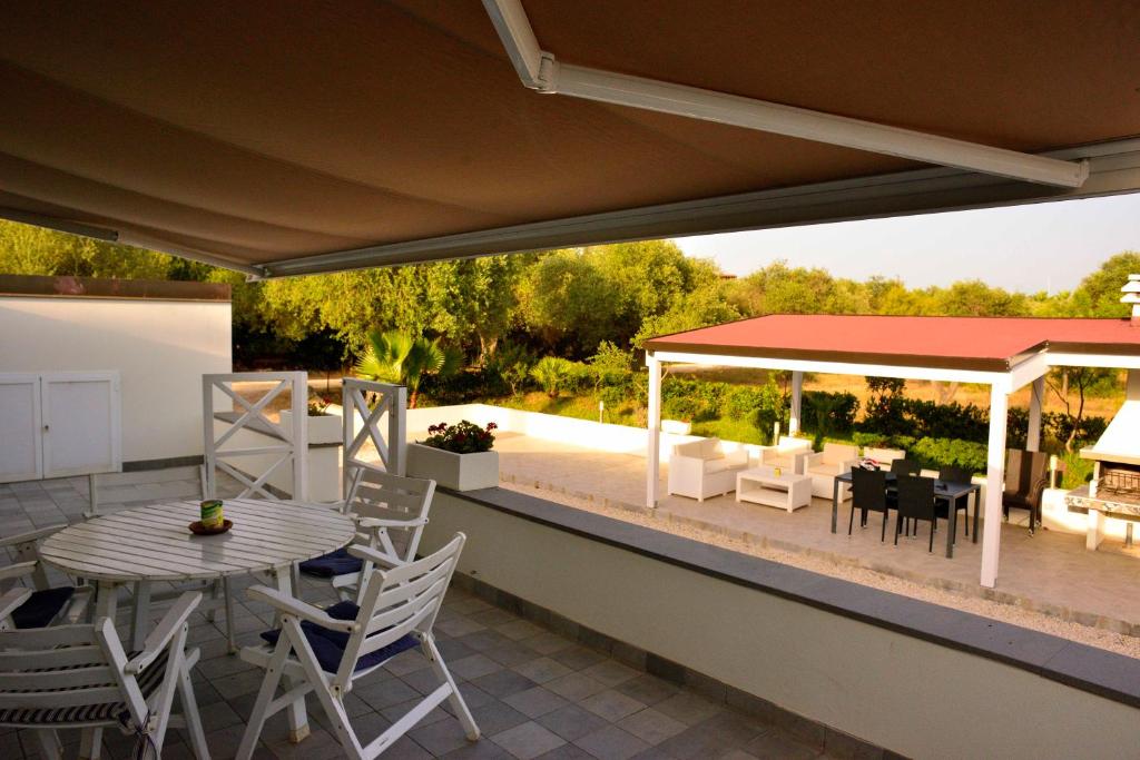 een patio met een tafel en stoelen en een prieel bij PM Villa Tania Guest House in Alghero