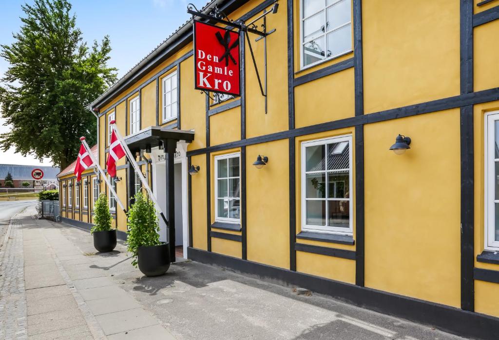 um edifício amarelo com bandeiras à frente em Den Gamle Kro Hornslet em Hornslet