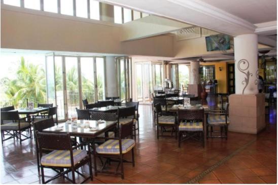 - une salle à manger avec des tables, des chaises et des fenêtres dans l'établissement Seafront Corus Resort Port Dickson, à Port Dickson