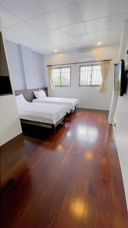 a bedroom with two beds and a wooden floor at Sun B&amp;B in Taitung City