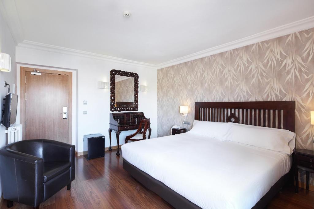 a bedroom with a bed and a chair and a mirror at Sercotel Hotel President in Figueres