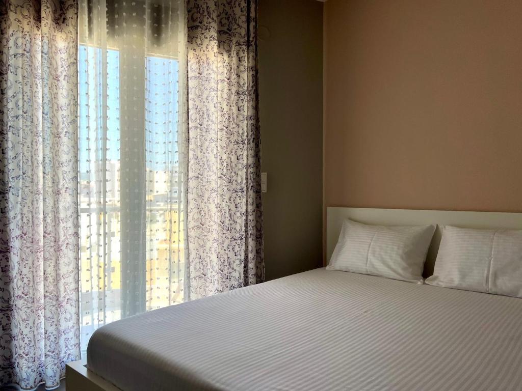 een slaapkamer met een bed en een raam met gordijnen bij SnappyB - Colours in Alexandroupoli