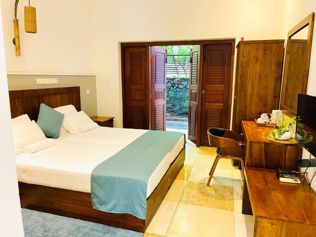 a bedroom with a bed and a desk and a television at Grand Rockland Hotel in Matara