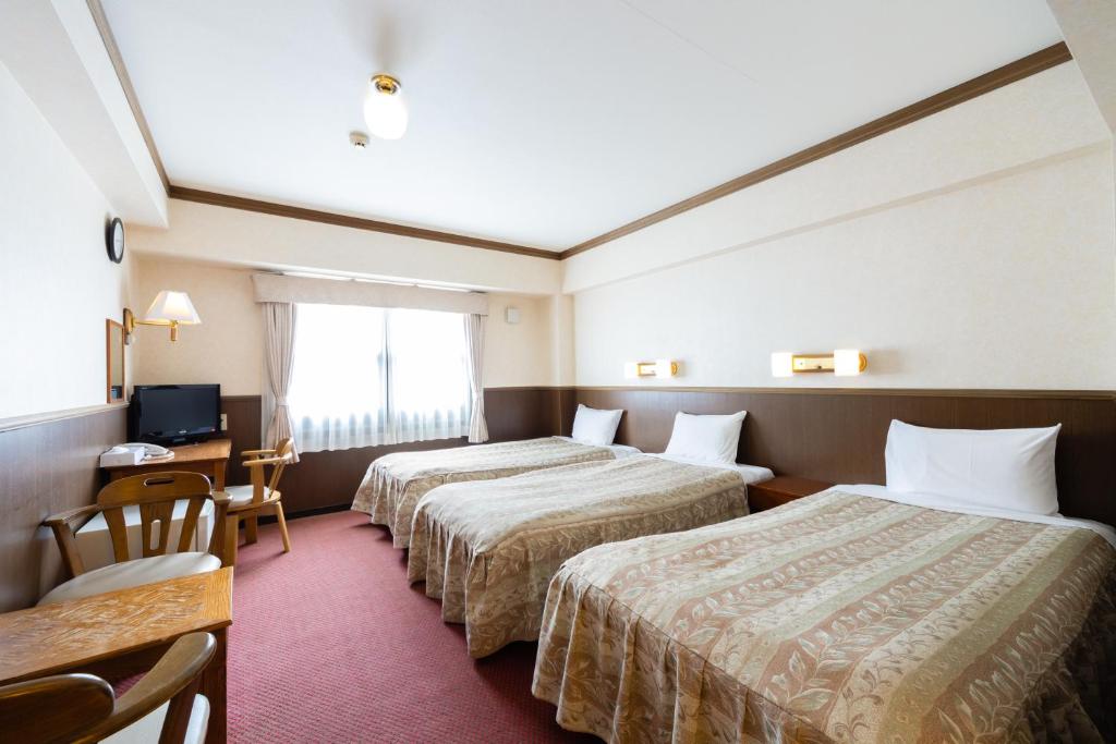 a hotel room with two beds and a desk at Gora Hotel Paipuno Kemuri Plus in Hakone