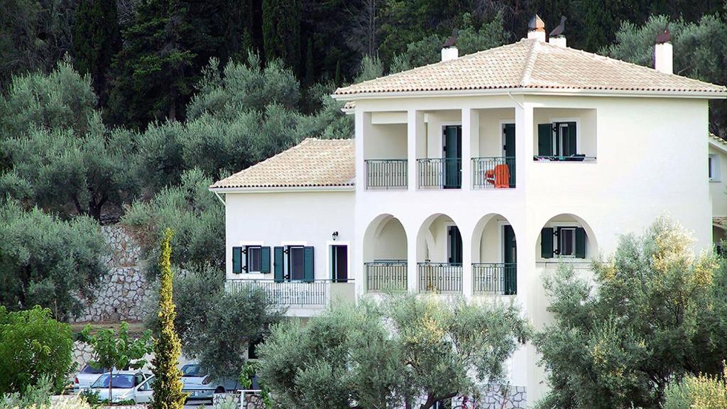 uma grande casa branca com varanda e árvores em Villa Evgenia em Yénion