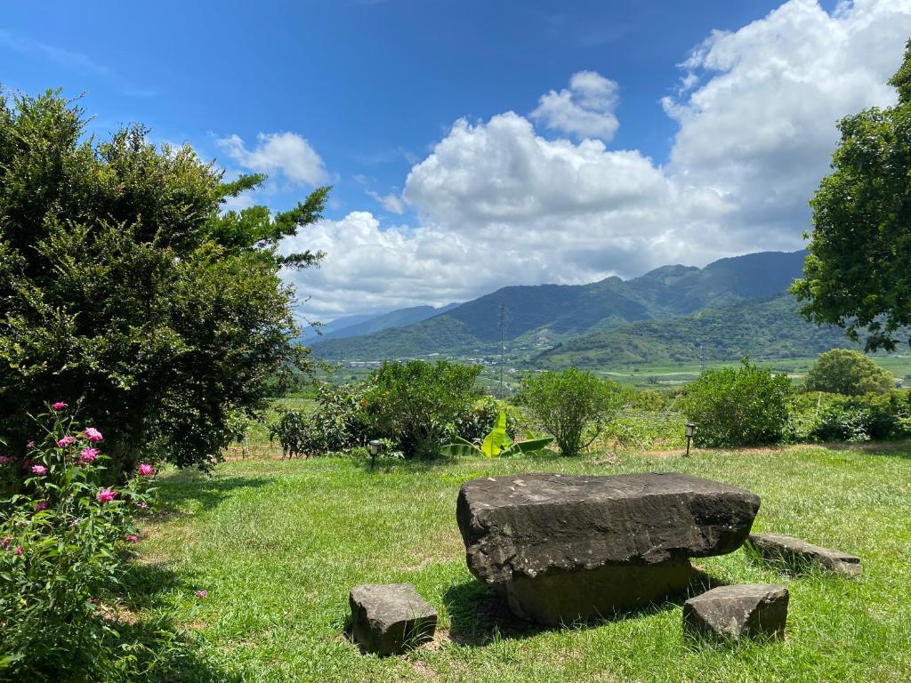 un banco de piedra en un campo con montañas en el fondo en Oh! Yosuw BnB, en Chulu