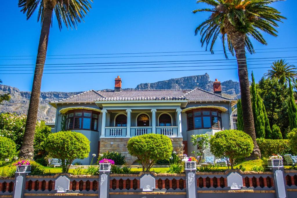 une maison avec des palmiers et des montagnes en arrière-plan dans l'établissement Cape Riviera Guesthouse, au Cap