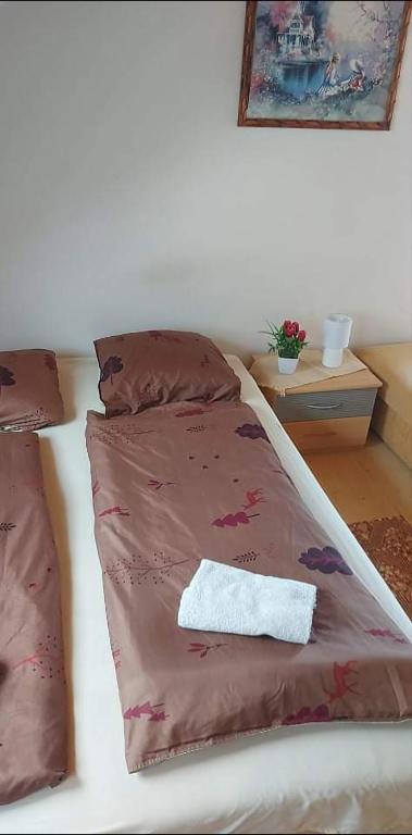 ein Bett mit einer braunen Bettdecke und einem Handtuch darauf in der Unterkunft Badacsonyi privát bérlemény in Badacsonytomaj