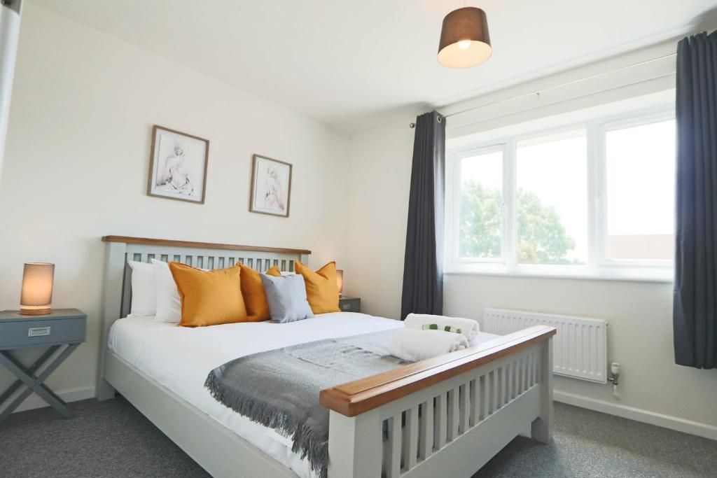 1 dormitorio con 1 cama con almohadas de color naranja y ventana en 2 Bedroom house in Bradley Stoke- Hopewell, en Bristol
