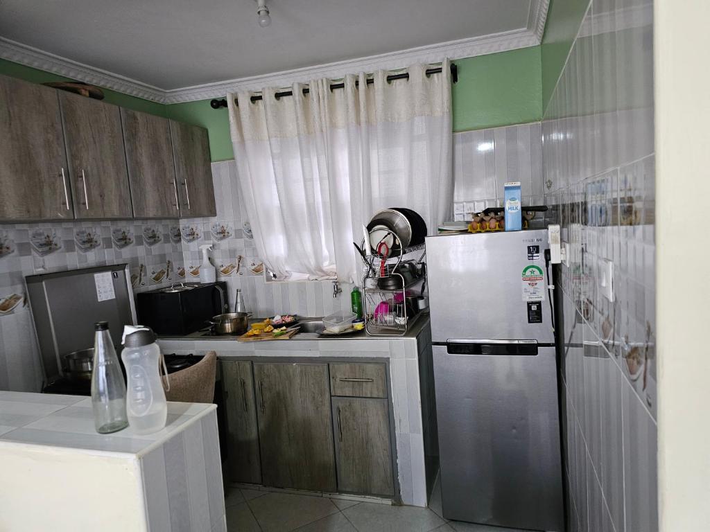 eine Küche mit einem weißen Kühlschrank und Holzschränken in der Unterkunft Ngomg in Nairobi