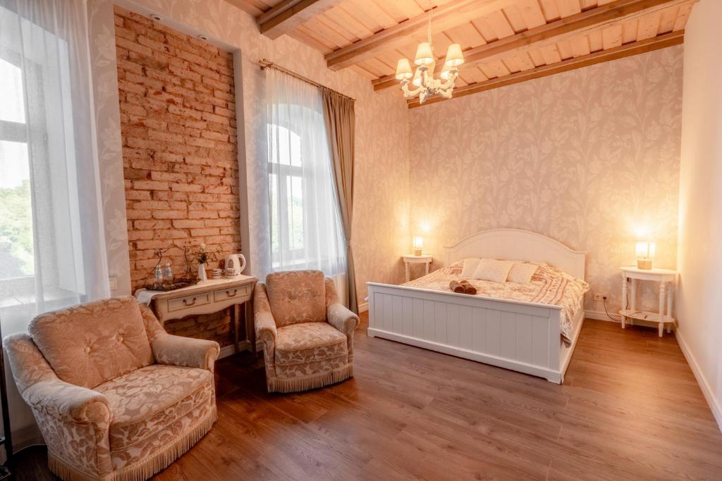 a bedroom with a bed and two chairs in it at Dēseles dzirnavas - Guest House in Embūte
