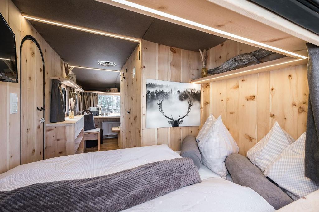 1 dormitorio con 1 cama en una habitación con paredes de madera en Mountain Caravan - Zirben Nestl, en Nova Ponente