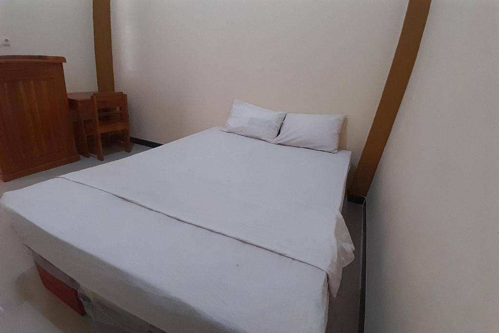 ein Bett mit weißer Bettwäsche und einem Kissen darauf in der Unterkunft OYO Life 92812 Galih Kostel 2 Syariah in Grobogan