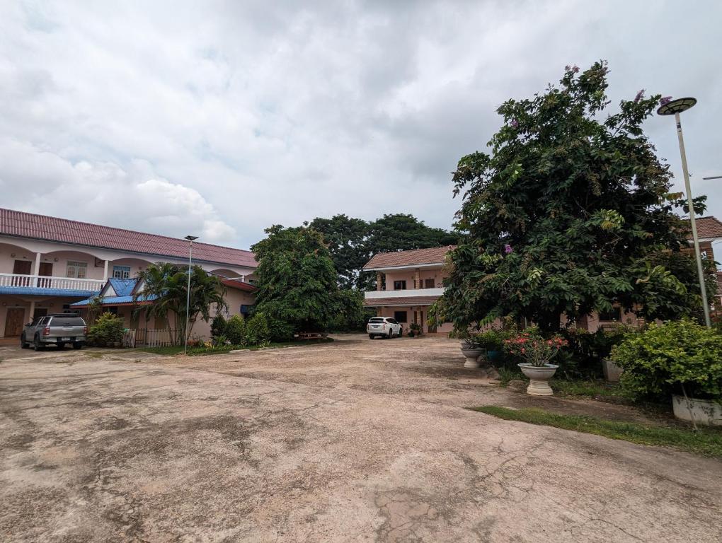 a dirt parking lot in front of a group of buildings at Alongkon Mansion in Sakon Nakhon