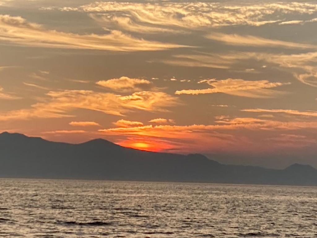 um pôr-do-sol sobre o oceano com montanhas ao fundo em ＯＫＵＮＯ ＩＥ em Oshima
