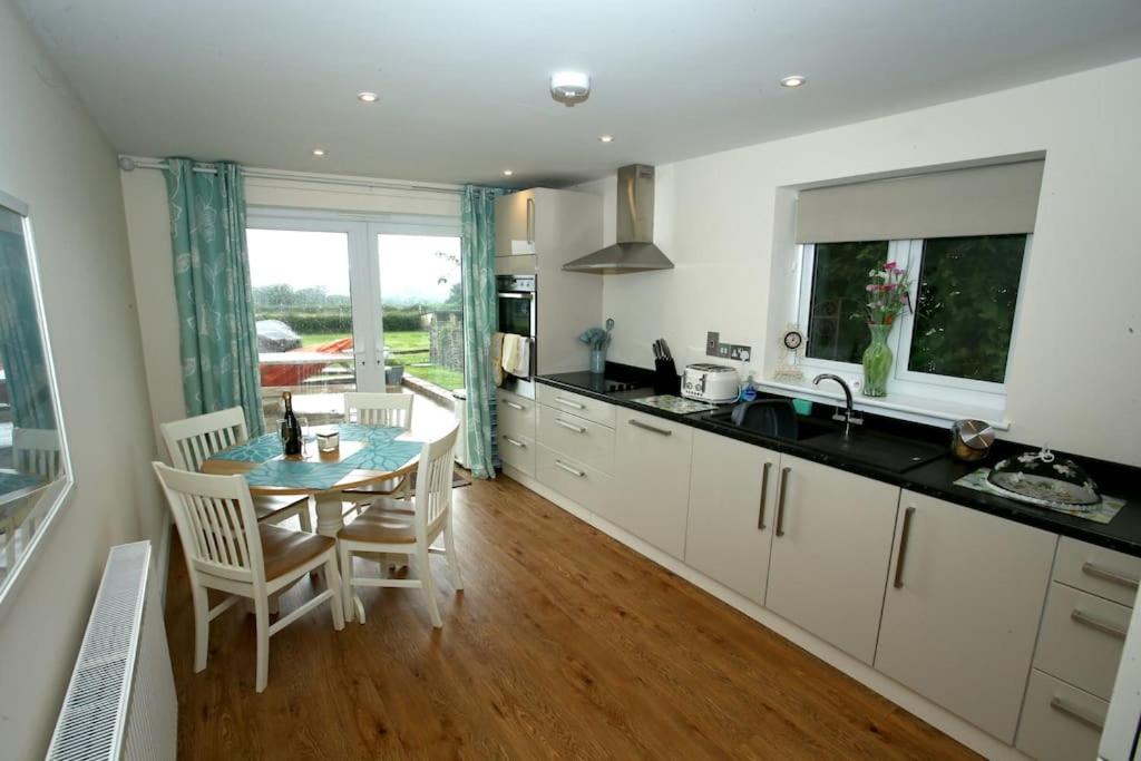 a kitchen with a table and a dining room at Lovely two bedroom bungalow with hot tub in Yeovil