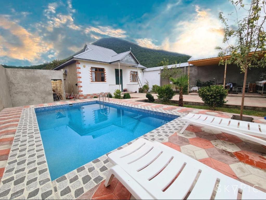 een zwembad met witte stoelen en een huis bij Nasimi Villa in Gabala
