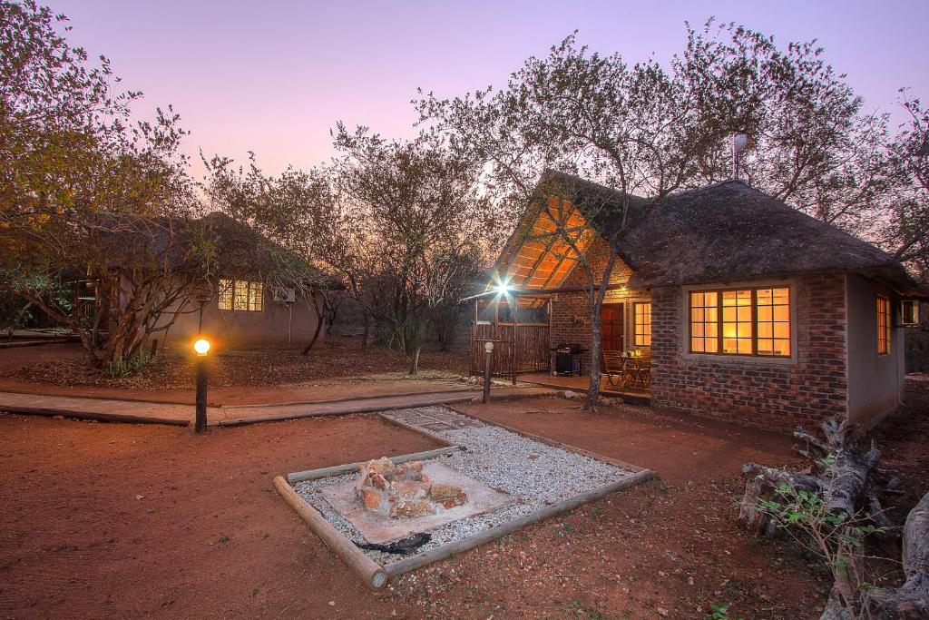 a house with a fire pit in front of it at South Safari Lodge in Marloth Park