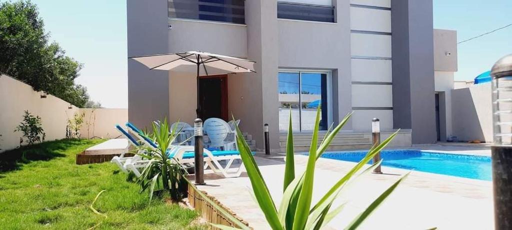 a house with a swimming pool and an umbrella at MAISON RITEl 1 in Taguermess
