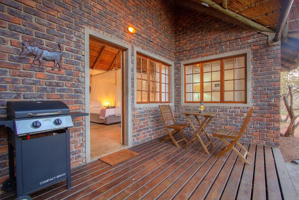 patio con piano cottura e tavolo su un muro di mattoni di South Safari Lodge a Marloth Park