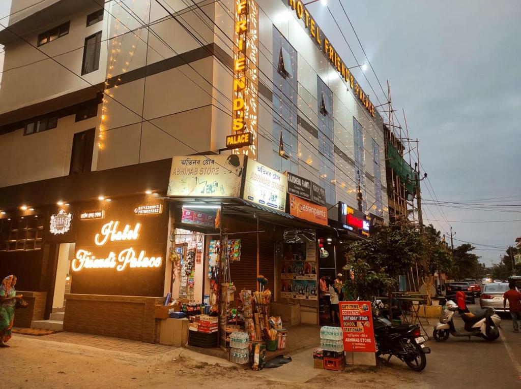 un magasin sur le côté d'un bâtiment avec des panneaux de néons dans l'établissement Hotel Friends Palace, à Tezpur