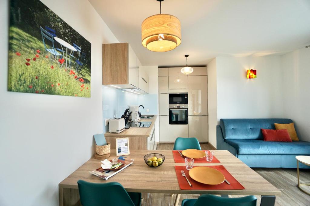 ein Wohnzimmer mit einem Tisch und einem blauen Sofa in der Unterkunft L'Escale in La Forêt-Fouesnant