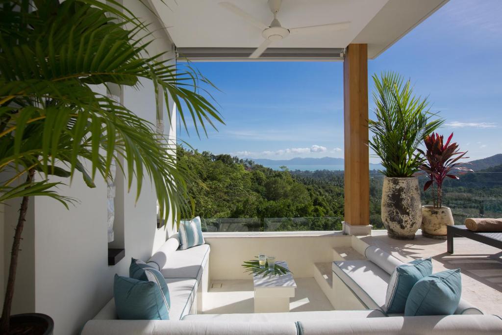 a living room with white furniture and a large window at Zog Villas in Koh Samui 