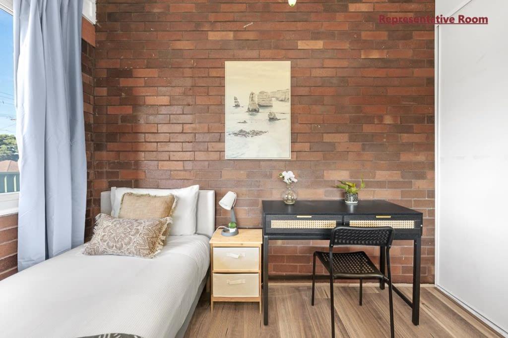 a bedroom with a brick wall with a bed and a desk at Comfort Single Room - Private - Prime Spot in Sydney
