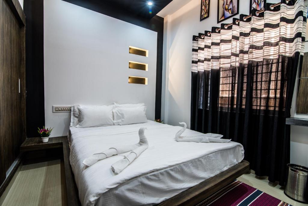1 dormitorio con 1 cama grande con sábanas blancas en Kanasu StayHome, en Chikmagalur