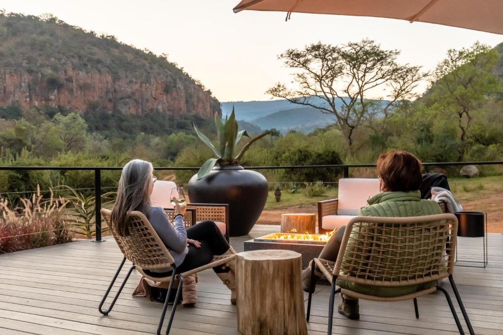 dos mujeres sentadas en sillas en una terraza con vistas en Mbizane Escarpment Retreat en Schoemanskloof