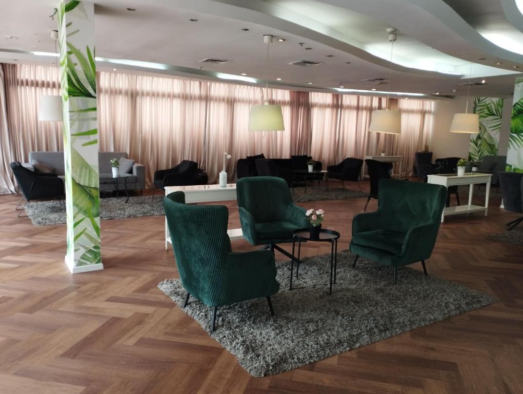 poczekalnia z zielonymi krzesłami i stołami w obiekcie Park hotel w mieście Netanja