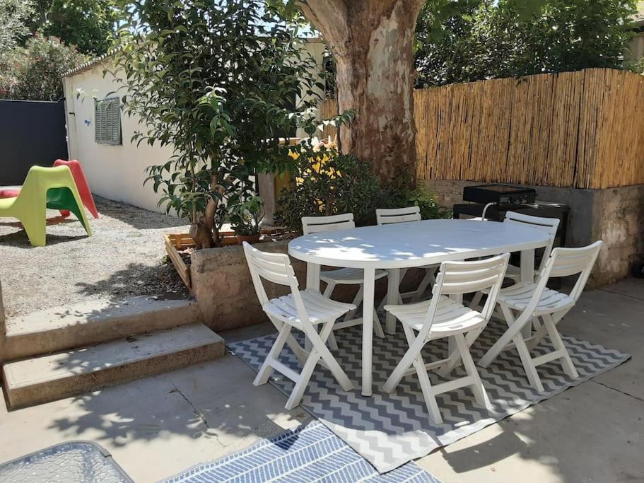 - une table et des chaises blanches dans la cour dans l'établissement Maison avec jardin, à Marseille