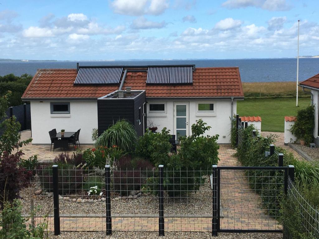 a white house with solar panels on top of it at Casa Uno North - Nice appartement for two with sea view in Farsø