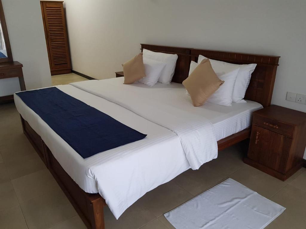 um quarto com uma cama grande com lençóis brancos e almofadas em Tortuga Beach Hotel em Paiyagala South