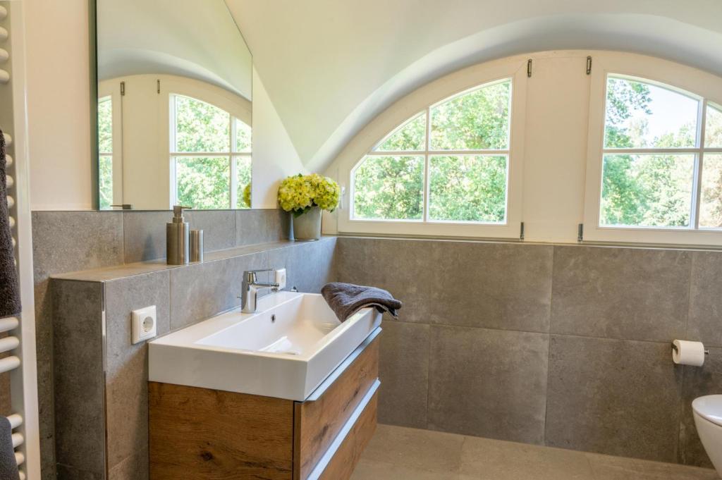 ein Badezimmer mit einem Waschbecken und zwei Fenstern in der Unterkunft Lieblingshof in Born