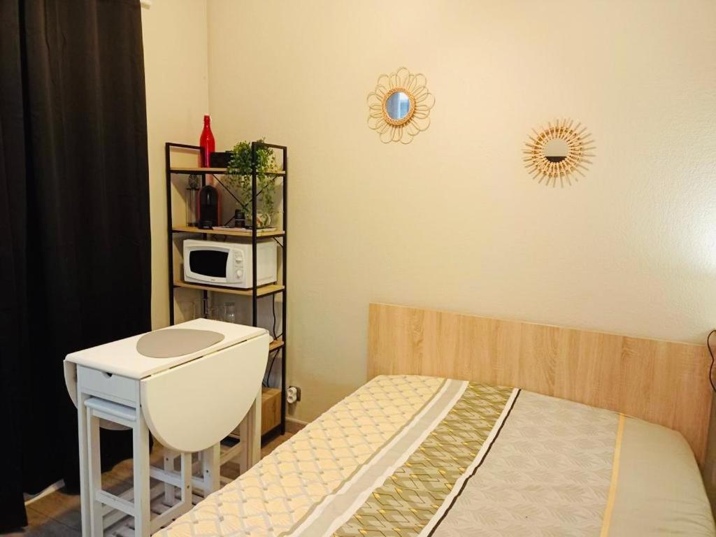 Schlafzimmer mit einem Bett, einem Tisch und einer Mikrowelle in der Unterkunft Appartement calme et bien situé in Tarbes