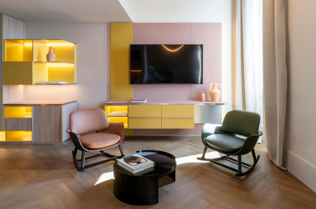 a living room with two chairs and a desk at Palazzo Tirso MGallery Cagliari in Cagliari