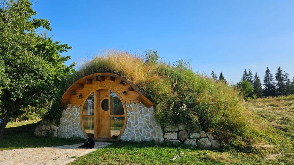 uma pequena casa com um telhado de relva numa colina em Mountain bungalows and a Hobbit House - Jazavčije Rupe em Han Pijesak
