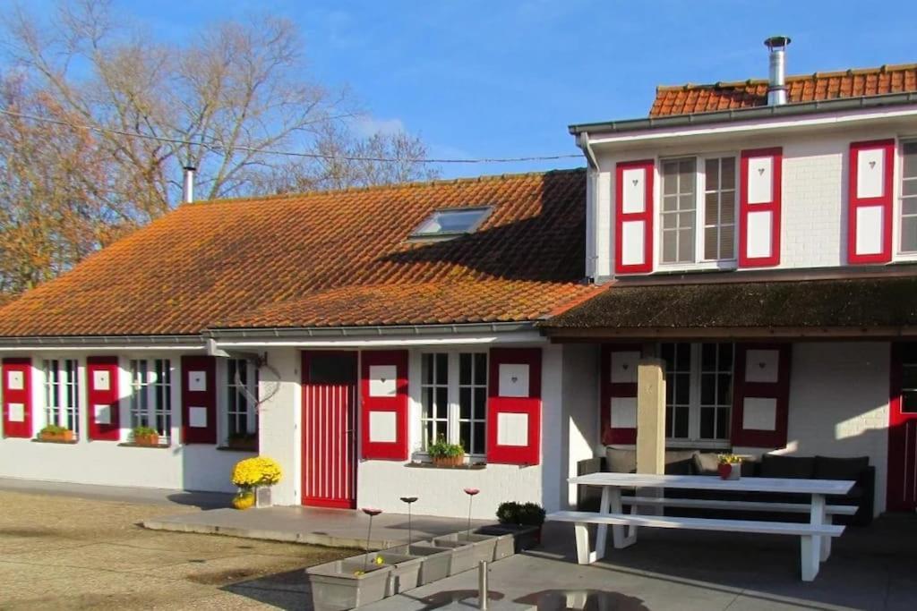 una casa roja y blanca con un banco delante en Hof ter Harte, en Ypres