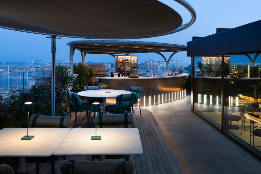 a rooftop bar with tables and chairs on a building at Palazzo Tirso MGallery Cagliari in Cagliari