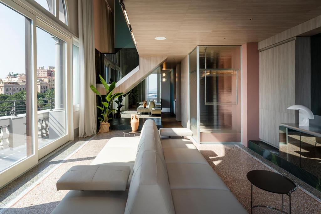 a living room with a white couch and large windows at Palazzo Tirso MGallery Cagliari in Cagliari