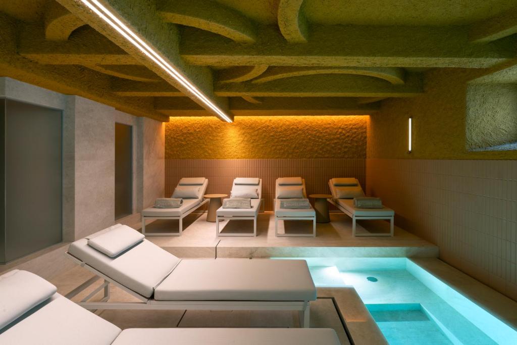 a waiting room with chairs and a pool at Palazzo Tirso MGallery Cagliari in Cagliari