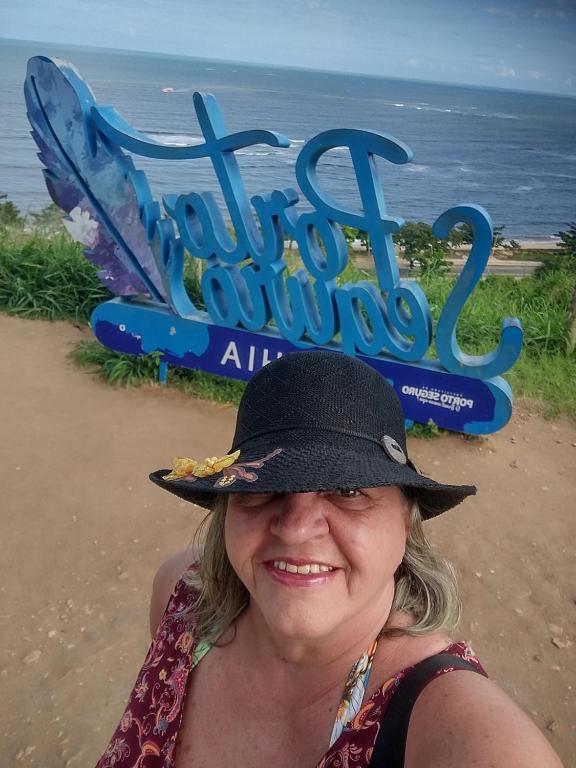 Una mujer con un sombrero frente al océano en Casa da Mila en Porto Seguro